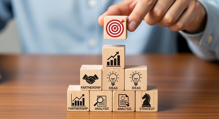 Wooden blocks stacked to represent business strategy and goals, with a hand placing the target block on top, symbolizing success and achievement in a structured plan