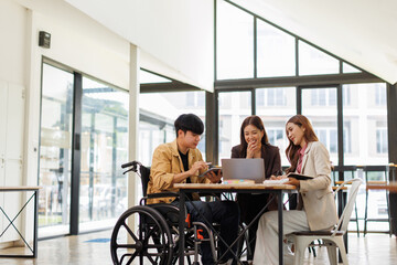 Asian Male Manager On A Wheelchair Sitting With His Colleagues At Workplace
