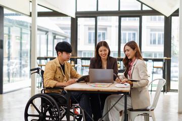 Asian Male Manager On A Wheelchair Sitting With His Colleagues At Workplace
