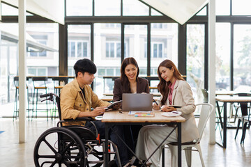 Asian Male Manager On A Wheelchair Sitting With His Colleagues At Workplace
