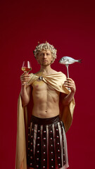 Roman man in toga holding wine glass and fish on fork against red backdrop. Concept of restaurant branding, food advertising, lifestyle imagery, and creative culinary campaigns.