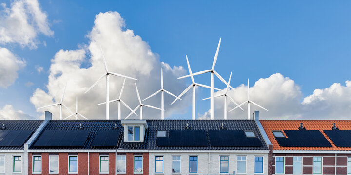 Row of new modern Dutch family houses in front of a field with large wind turbines