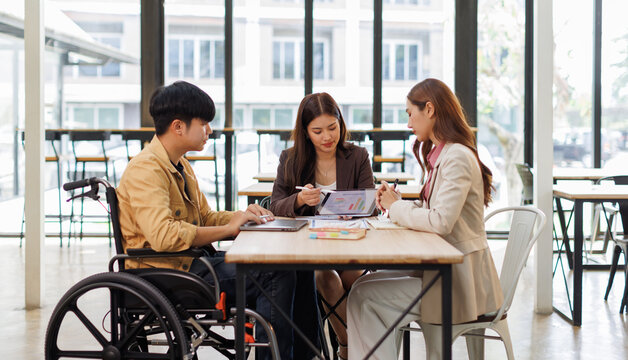 Group of business people in a meeting with man on a wheelchair for inclusion. Young businessman greeting business partner and team. Coworker on wheelchair
 - Powered by Adobe