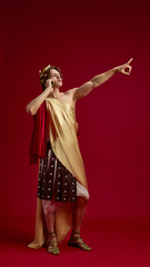 Young man in toga talking on phone with pointing gesture. Concept of modern communication in antique style, customer service, social media storytelling, and branding promotion.