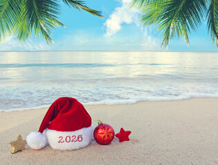 Merry Christmas background with red hat and decorations on Caribbean sand.