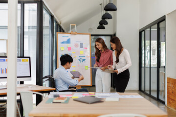 Happy business man on wheelchair and her female colleague cooperating while working on paperwork in the office.

