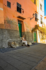 Momento di quiete a Camogli: donna con cane su panchina tra colori e luce mediterranea