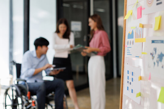 Group shot of diverse business people, disabled asian man on wheelchair chatting with colleagues together at meeting room at office
 - Powered by Adobe