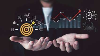 Hands holding holographic display of business growth metrics with target, rising charts, profit symbols, and health indicators. Concept of financial success and strategic business planning.