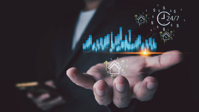 Person in suit holding hand with holographic graphs, glowing house icons, upward arrows, percentages, money symbols, and 24 clock. Concept of growth and continuous real estate investment.