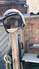 Pink motorcycle helmet on wooden post in urban courtyard — contrasting image of safety, style,...