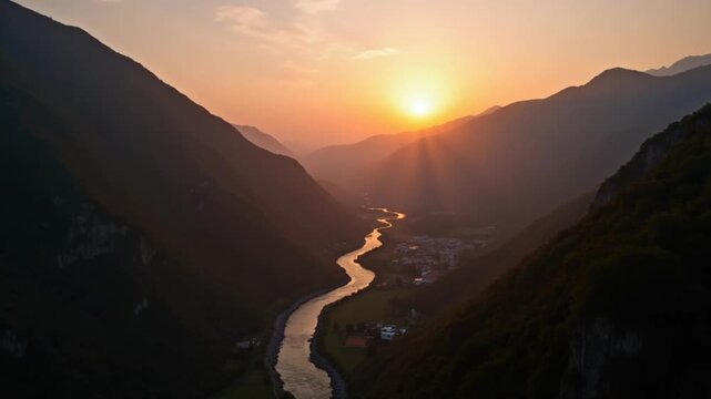 Drone view of a sunset in a valley with a river and mountain ranges