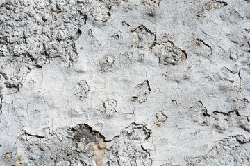 A close-up shot of an old, damaged wall with peeling paint and a heavily cracked, weathered texture