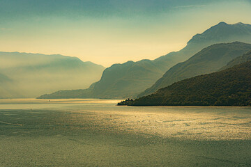Morgenstimmung am Lago di Como mit spiegelnder Wasserfläche; Blick von Piona nach Menaggio