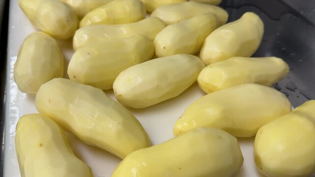peeled raw potatoes on white cutting borad in a kitchen