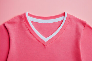 Closeup of a pink tshirt with a white vneck collar on a pink background, showcasing the garments design and color combination for fashion appeal