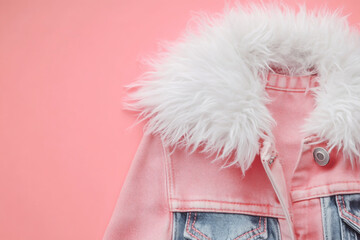 Pink denim jacket with a white faux fur collar on a pink background, creating a stylish and trendy look for fashionconscious individuals