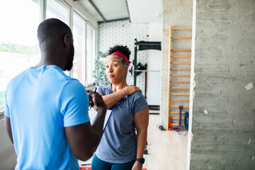 Personal trainer assisting client in gym
