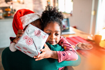 Little girl hugging her father during christmas for receiving a gift 