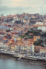 Fototapeta premium A scenic cityscape shows traditional buildings with red tile roofs cascading down a hillside in the Ribeira district of Porto, Portugal on an overcast day