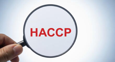Magnifying Glass Enlarging the Text HACCP on a White Surface Representing Food Safety, Hazard Analysis, and Critical Control Points in Quality Assurance