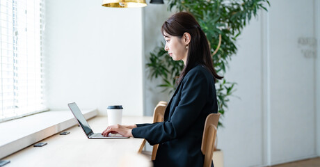 室内でパソコン作業をするスーツを着た女性