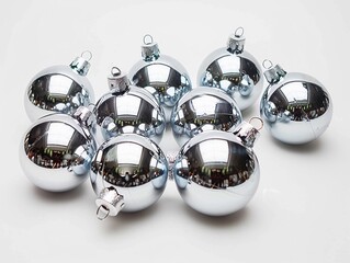 Shiny silver Christmas ornaments arranged in a circular pattern on a white surface