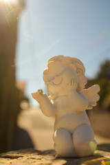 Plaster figurine of a white Angel holding a small zircon gem in his hand with a smile on his face....