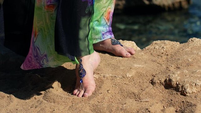 Female in beautiful beach dress and oriental style leg jewelry on sand