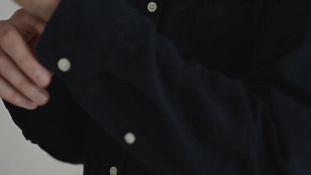 Close-up detail of a buttoned black shirt indoors. The shot emphasizes attention to appearance, professional preparation, and business confidence. High quality 4k footage