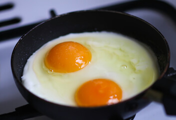 Fried eggs in pan with bright yellow yolks.