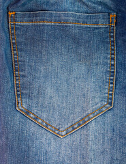 A close-up of a back pocket on blue jeans. The classic denim pocket with its light-colored double stitching is an iconic and timeless element of casual fashion design