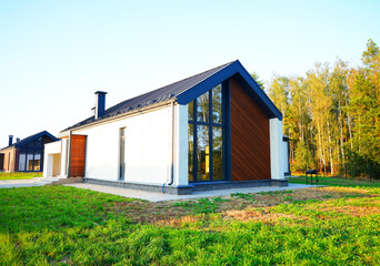 Modern Barn house in white and wooden exterior in bright rural. Prefab house. Loft Farmhouse in suburb. Family house in barn style project. Modern barnhouse With Wooden Accents in Sunny Rural Setting. © MaxSafaniuk