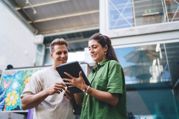 Woman using stylus to interact with tablet while man engages in discussion, capturing real-time...