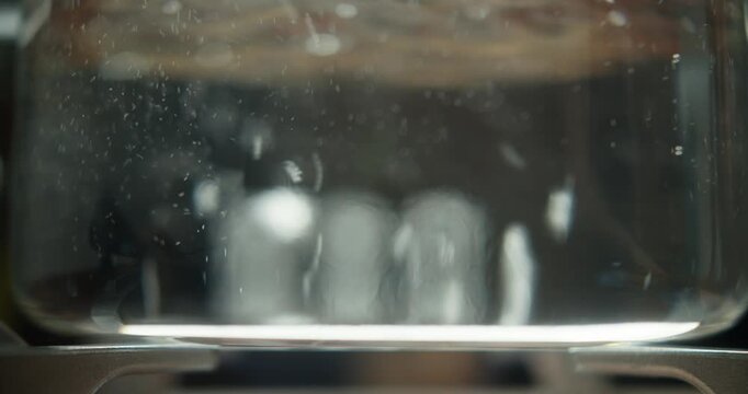 Boiling water in a transparent pan on a gas stove. Filmed in RAW format. High-quality 4K video.