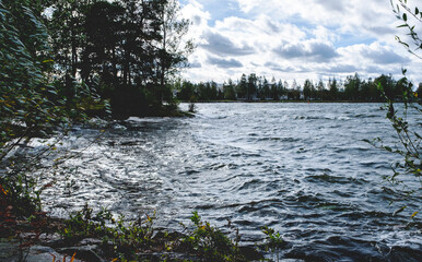 Autumn landscape, lake and wooded area. Strong wind, waves on the lake.