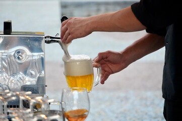 Barman pouring beer into a glass from the coffee machine, close-up