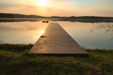 Romantic jetty on the lake at sunset with calm water