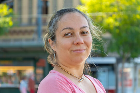 Street portrait of a dark-haired woman aged 40-45 years on the background of a city street.