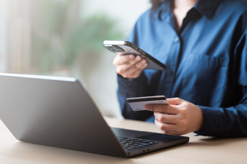 Person using credit card with smartphone and laptop for online shopping, representing e-commerce.
