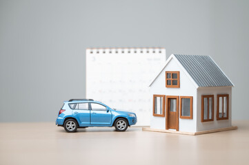 Model house and car with calendar, symbolizing monthly payment, debt management, financial planning, property investment, and long-term asset management.