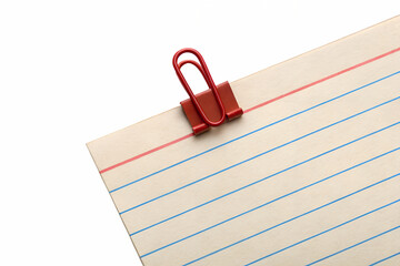 Red binder clip holding lined paper isolated on white background
