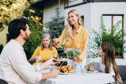 Family enjoying dinner together in the backyard of their house - Powered by Adobe