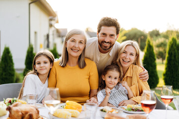 Happy family enjoying outdoor meal in backyard hugging together looking at camera