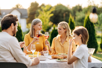Family enjoying dinner together in the garden, toasting with wine