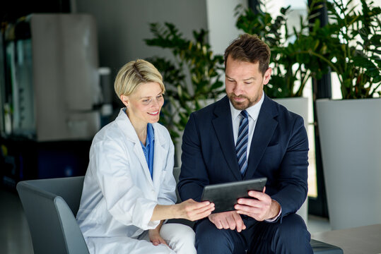 Pharmaceutical sales representative introducing new medication to female doctor. - Powered by Adobe