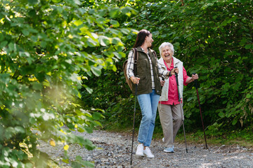 Senior woman and daughter enjoying hike with trekking poles.