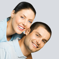 Love, dating, lovers, romantic concept - portrait of happy smiling cute young couple, in piggyback pose, isolate grey gray wall background. Square image