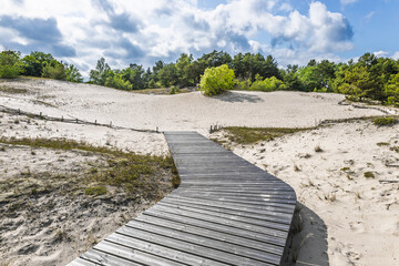 Wooden boardwalk across white sand dunes in coastal Latvia, Baltic landscape