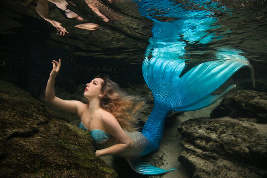 Woman dressed in a mermaid costume swimming underwater